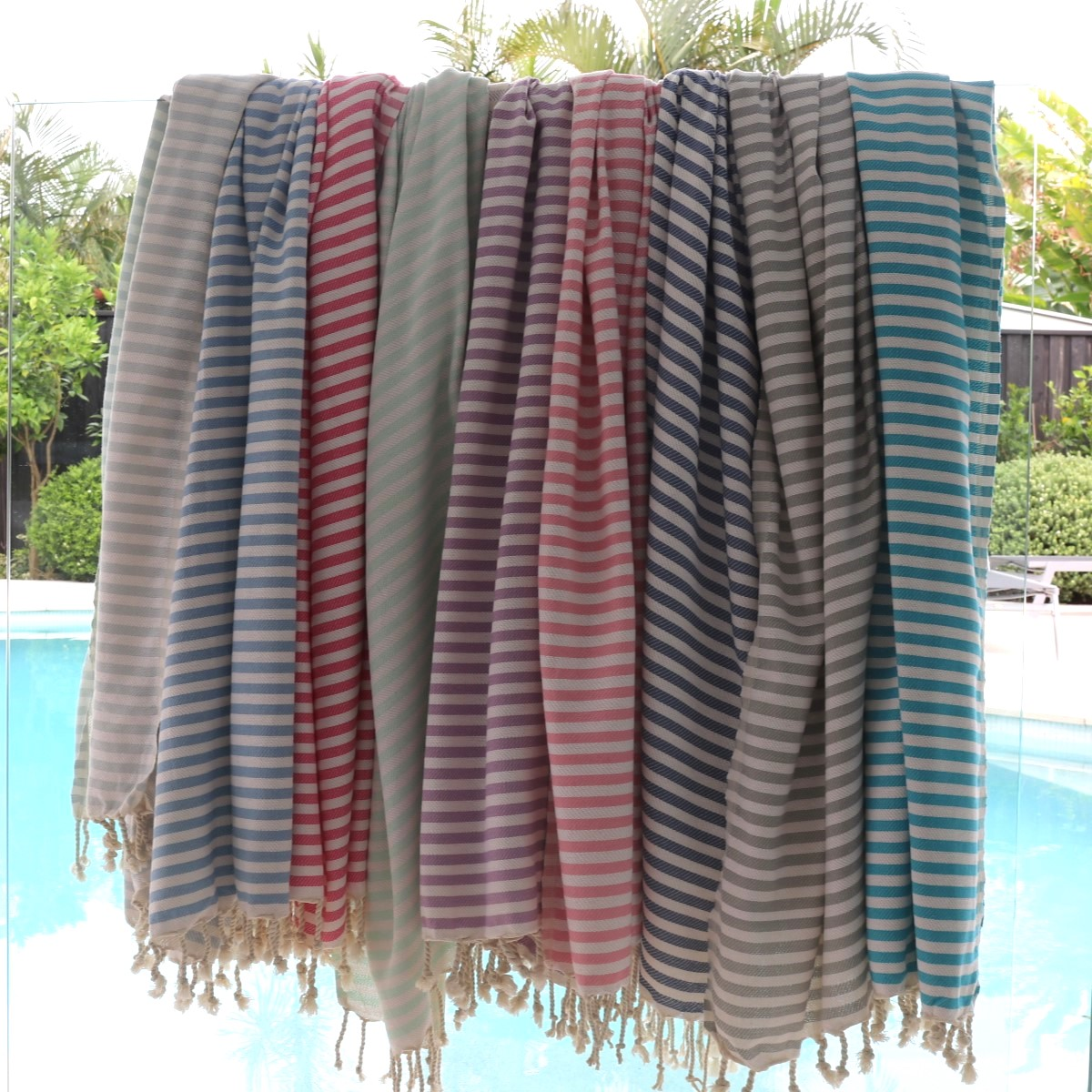 Bronte turkish beach towels over a pool fence in multiple colours