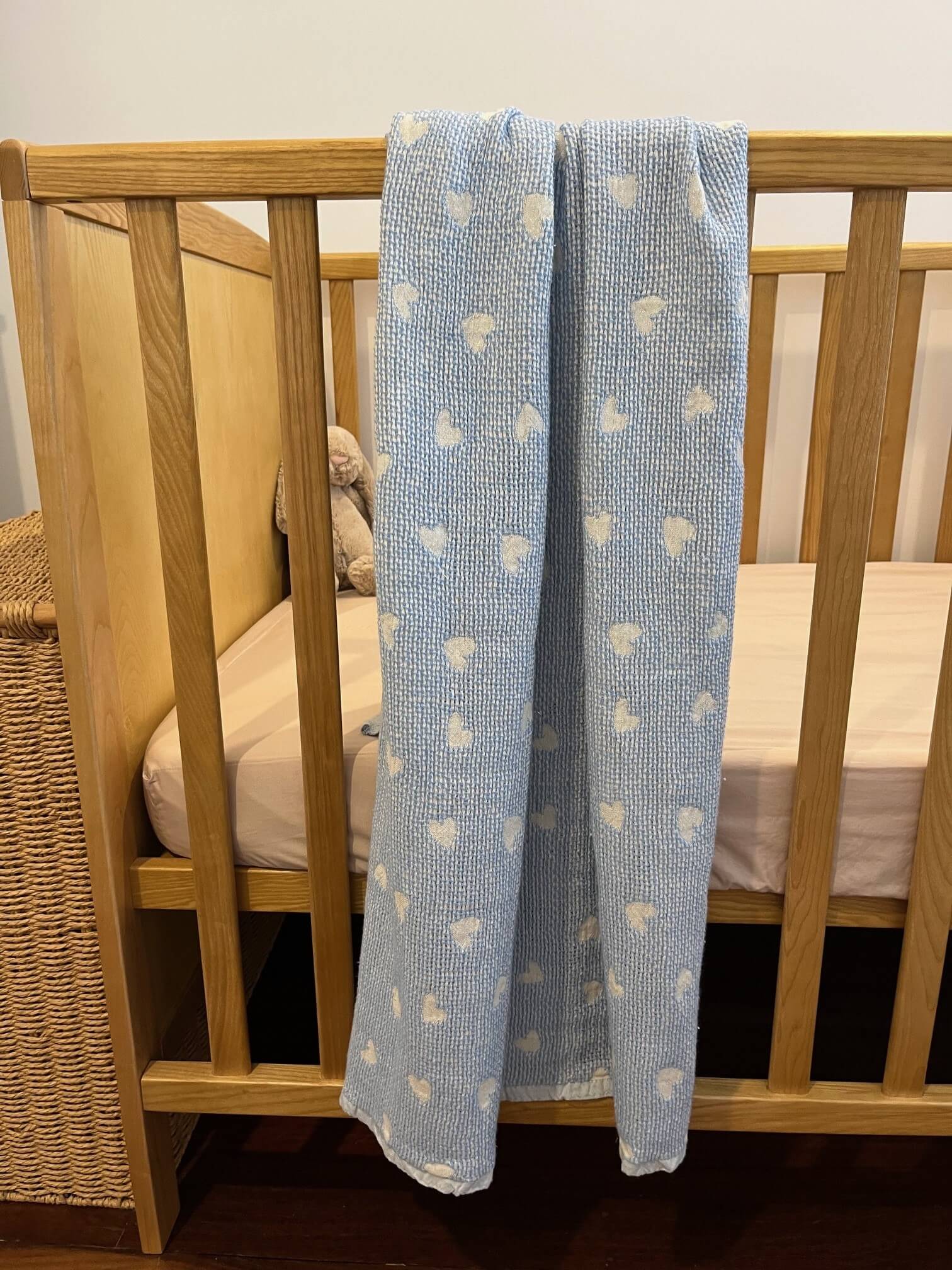 blue hearts cotton baby blanket displayed on a cot