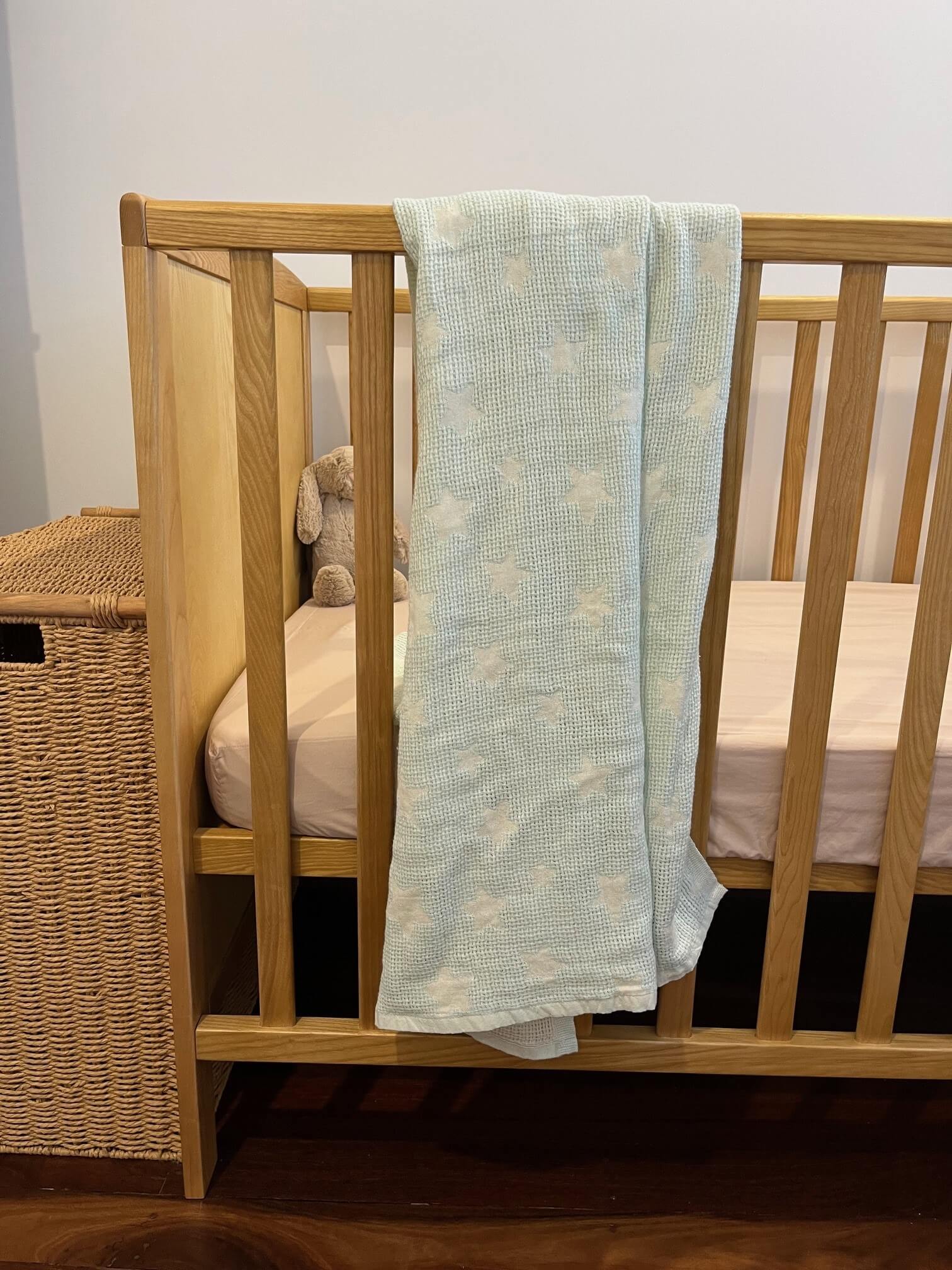 mint stars baby blanket displayed on a cot