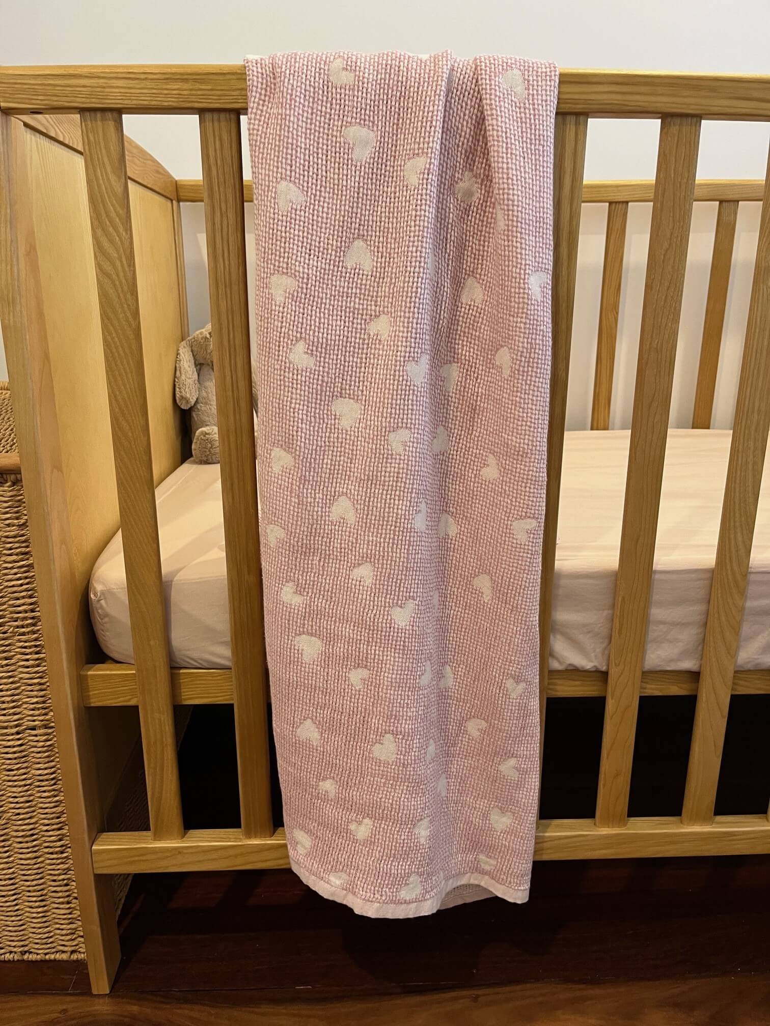 pink hearts baby blanket displayed on a cot