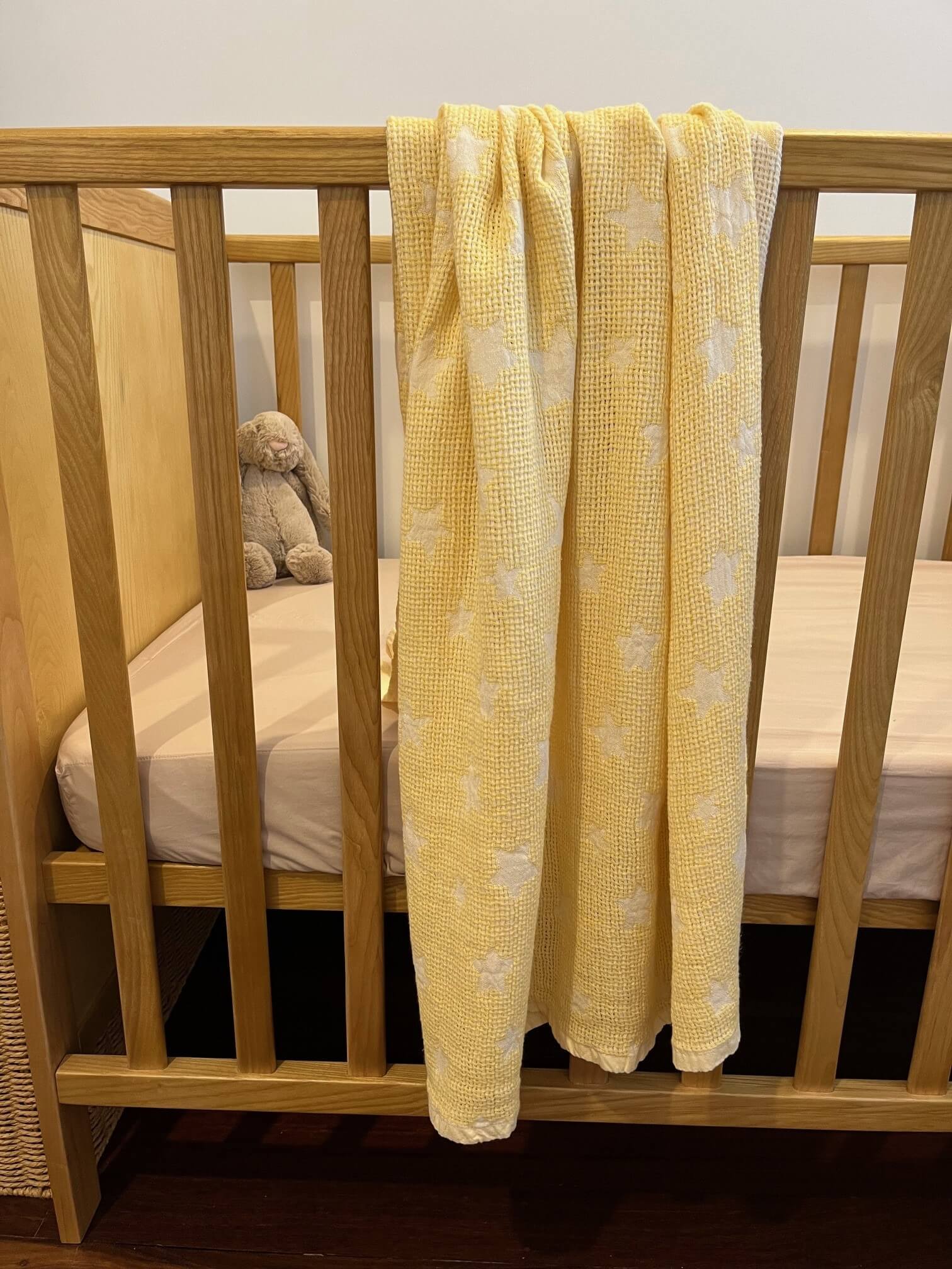 yellow stars baby blanket displayed on a cot